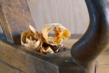 Old plane on wooden board, carpentry tools with wood shavings and sawdust 