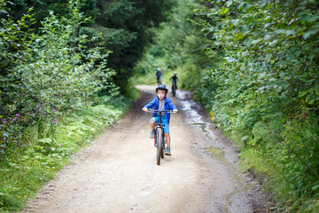 Small boy in helmet riding the bicycle on mountain road