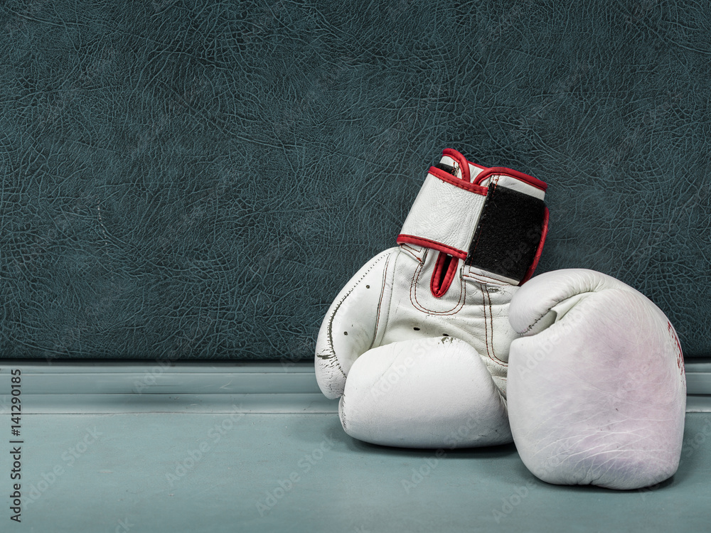 Wall mural a pair of white leather boxing gloves lying on the floor near a wall