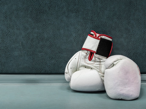 a pair of white leather boxing gloves lying on the floor near a wall