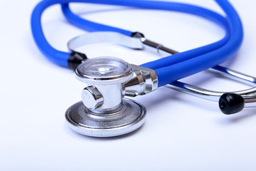 Medical stethoscope head lying on blue doctor uniform closeup. Medical tools and instruments shop, therapeutist workspace, physical, blood pressure measurement concept