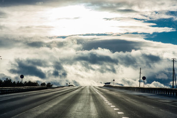 Highway under the dramatic cloudy and sunny sky in high contrast