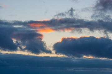 Dramatic blue clouds with a red sunset sunbeam