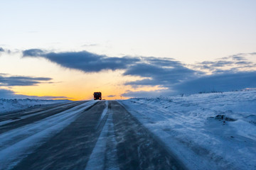 A lonely trucker driving in the blizzard at the dusk