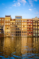 Naklejka premium Traditional old buildings and boats at sunset in Amsterdam, Netherlands.