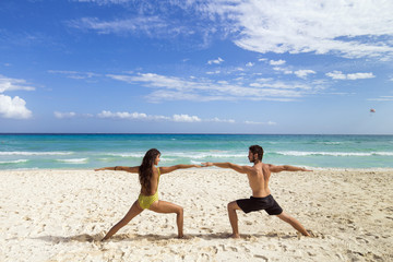 Couple practice yoga outdoors on the beach