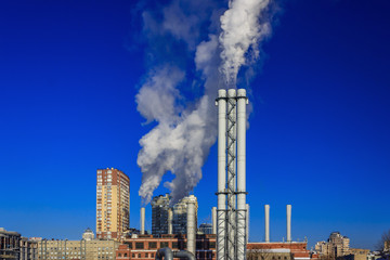 Fototapeta premium White smoke goes from a pipe on a background of blue cloudless sky