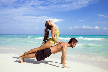 Couple practice yoga outdoors on the beach
