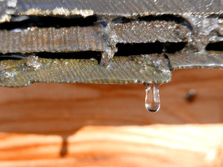 First day of spring, water drops falling from the snowy rooftop
