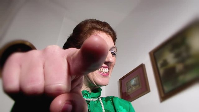 A harsh lady (woman in character) looking down at us and poking us in the eye with her finger. Funny comedy shot.
