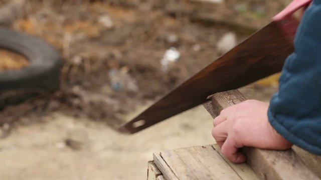 Man saws wooden bar rusty hand saw