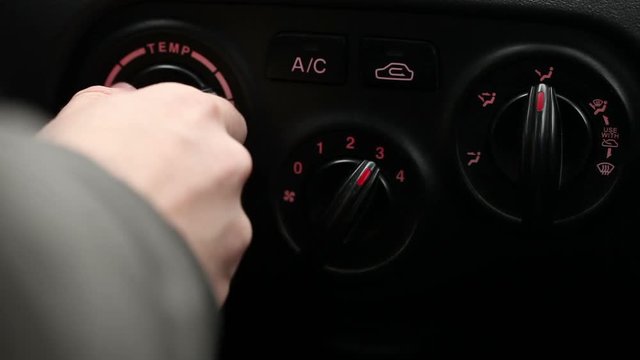 Man twists the knobs of climate control in the car.