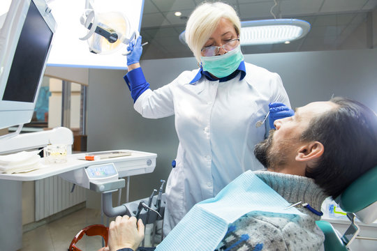 Dentist adjusting light. Female doctor and male patient. Restoration of teeth. - Powered by Adobe