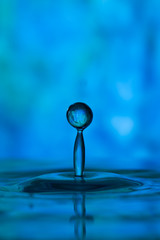 Fototapeta na wymiar Blue monochrome tie dye reflected in oblong water drop
