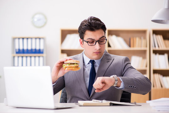 Hungry funny businessman eating junk food sandwich