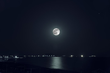 A beautiful night landscape of full moon over dark water with reflections on it © zef art