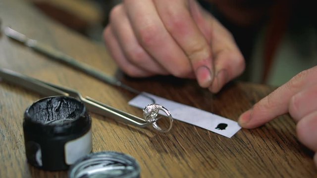 Jeweler enamels the silver ring with a special needle manually