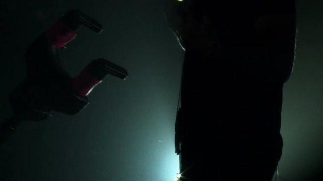 Musician plays on guitar in the backlighs and smoke