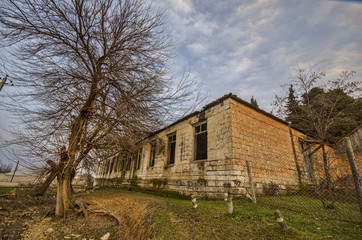 Obraz premium ground road in village in winter countryside the evening sunlight. atmospheric rural moment. Old house at road with trees at Gazakh Azerbaijan