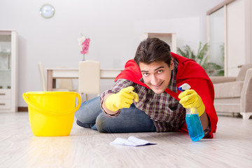 Naklejka premium Super hero husband cleaning floor at home