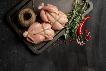 Farmer's chicken on a baking sheet with seasonal vegetables and greens before baking in the oven. Photo of food on a dark background for a book of recipes or design. Horizontal view. © Anton