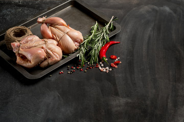 Farmer's chicken on a baking sheet with seasonal vegetables and greens before baking in the oven. Photo of food on a dark background for a book of recipes or design. Horizontal view. © Anton