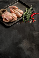 Cooking chicken with herbs and spice before baking in the oven. Dark background for a menu book of recipes or design. Vertical top view. Text area.  © Anton