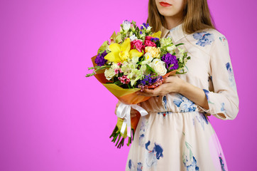 Beautiful girl in dress holding a bouquet of different flowers. Isolated