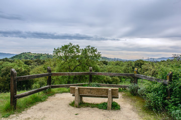 viewing platform with wood fence, mountains under cloudy sky
