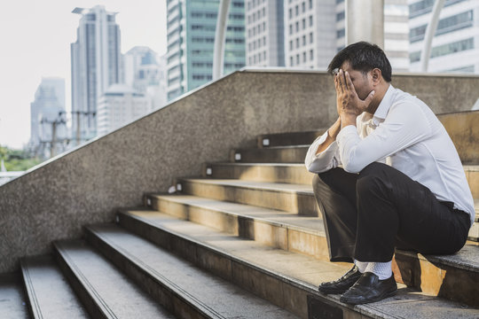 Young depressed businessman sitting on the stairs