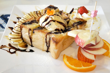 honey tost with ice cream and banana , strawberry apple whip cream and pour with chocolate. selective focus