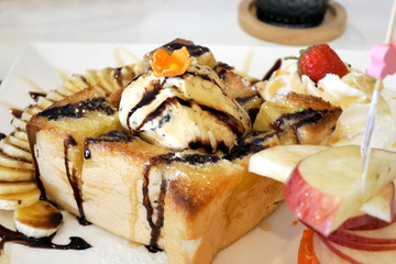 Honey tost with ice cream and banana , strawberry , apple , whip cream and pour with chocolate. selective focus