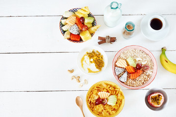 Breakfast set with tropical fruits. Oats with dragon fruit and papaya, cereal with melon, yogurt with passionfruit, bowl of tropical fruits, black coffee and milk. Space for text.