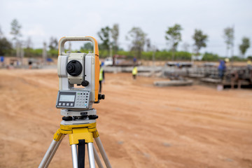 Surveyor equipment tacheometer or theodolite outdoors at construction site and construction worker in safety uniform - obrazy, fototapety, plakaty