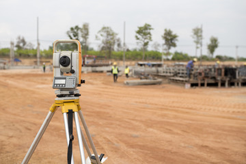 Surveyor equipment tacheometer or theodolite outdoors at construction site and construction worker...