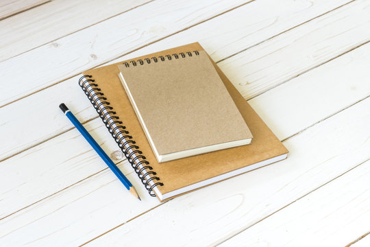 Notebook with blank pages and pencil on wood table
