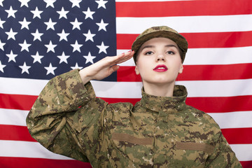 Woman soldier in uniform salute in front of  American flag. Portrait
