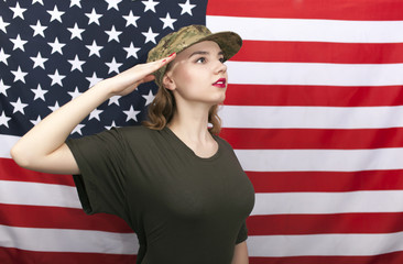 Woman soldier salute in front of  American flag  and looks afar