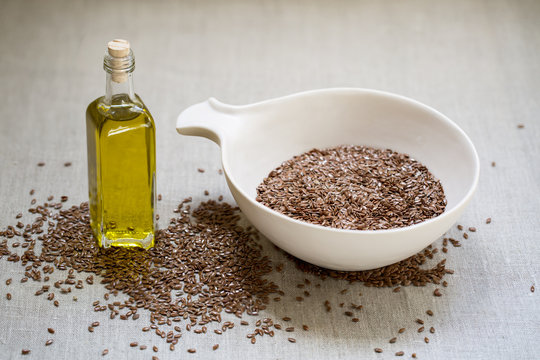 Flax seeds in bowl on linen cloth background 