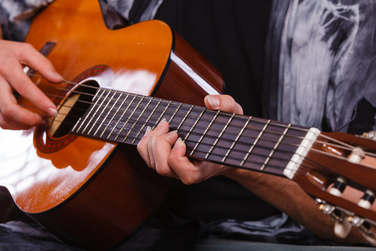 Closeup of man playing acoustic guitar