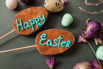 Fototapeta na wymiar Two easter cookies with a lettering and painted eggs with flowers on grey background. Easter greeting card