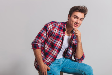 seated smiling young casual man holding chin