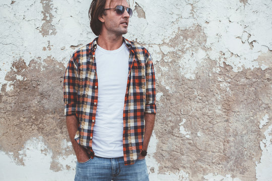 Man posing in blank white tshirt against street wal