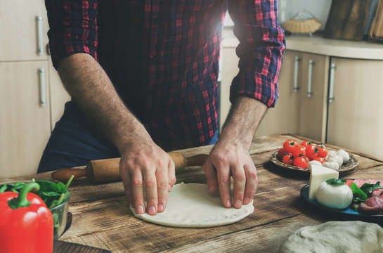 Man preparing dough for cooking homemade pizza in home kitchen