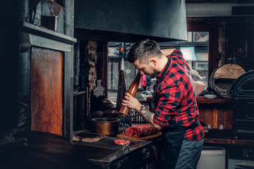 A man grilling a beef in a kitchen.