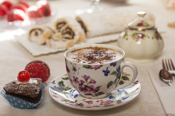 Italian breakfast with hot coffee cappuccino cup and chocolate muffins and sweet bakery. Sweet bakery and desserts in the background