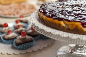 Close up of a cheesecake with strawberry jam. Muffin in the background. Breakfast icon