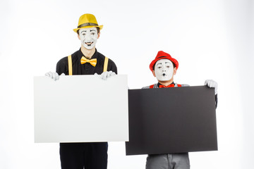 Two funny mimes holding a white blank on a white background.