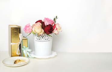 Home office white wall. A bouquet of roses and gold books