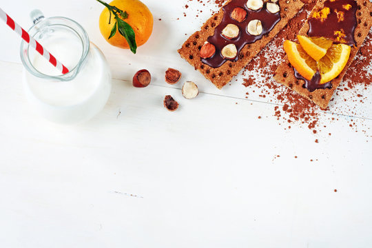 Healthy snack concept. Top view of chocolate sandwiches on crispbread and fresh milk on white table. Copy space.